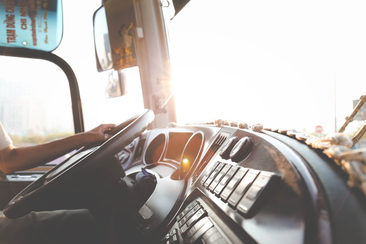 A bus driver navigating the city streets during a sunny day, focusing on the road.